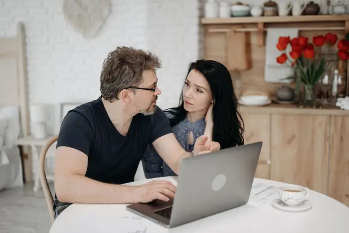 Pareja planeando en la mesa de su casa con su computadora